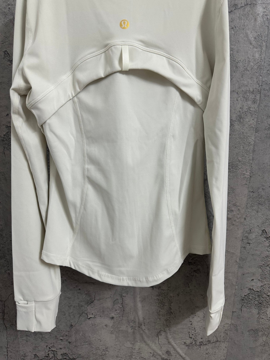 Light white zip-up jacket back view with waist seam shape and small gold logo at upper back.