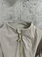 Beige jacket neckline with gold zipper and pull tab, close-up view