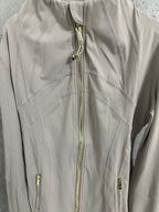 Light beige jacket front close-up with gold zipper and decorative seam stitching