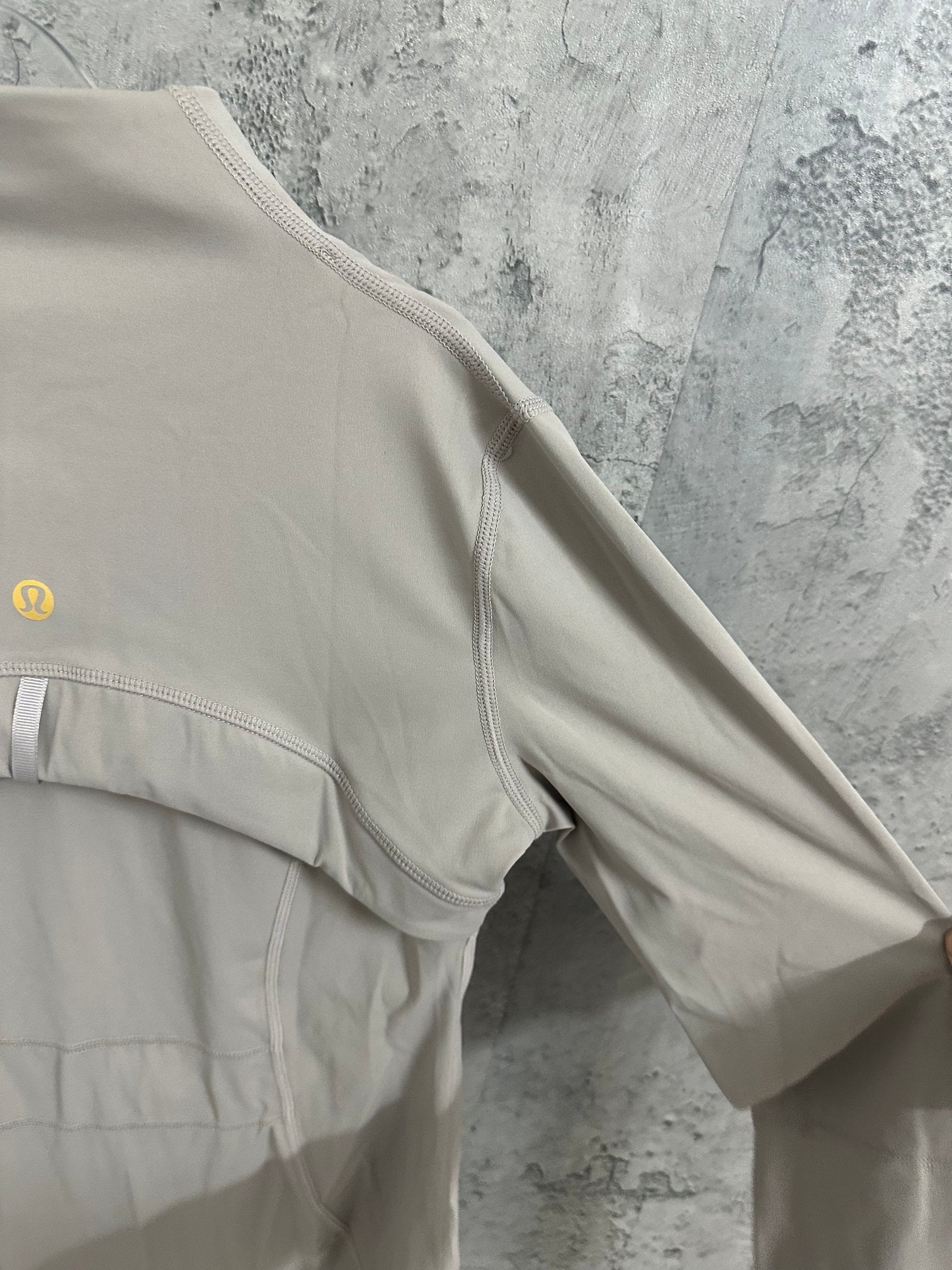 Light beige jacket shoulder and sleeve detail with stitched seam lines