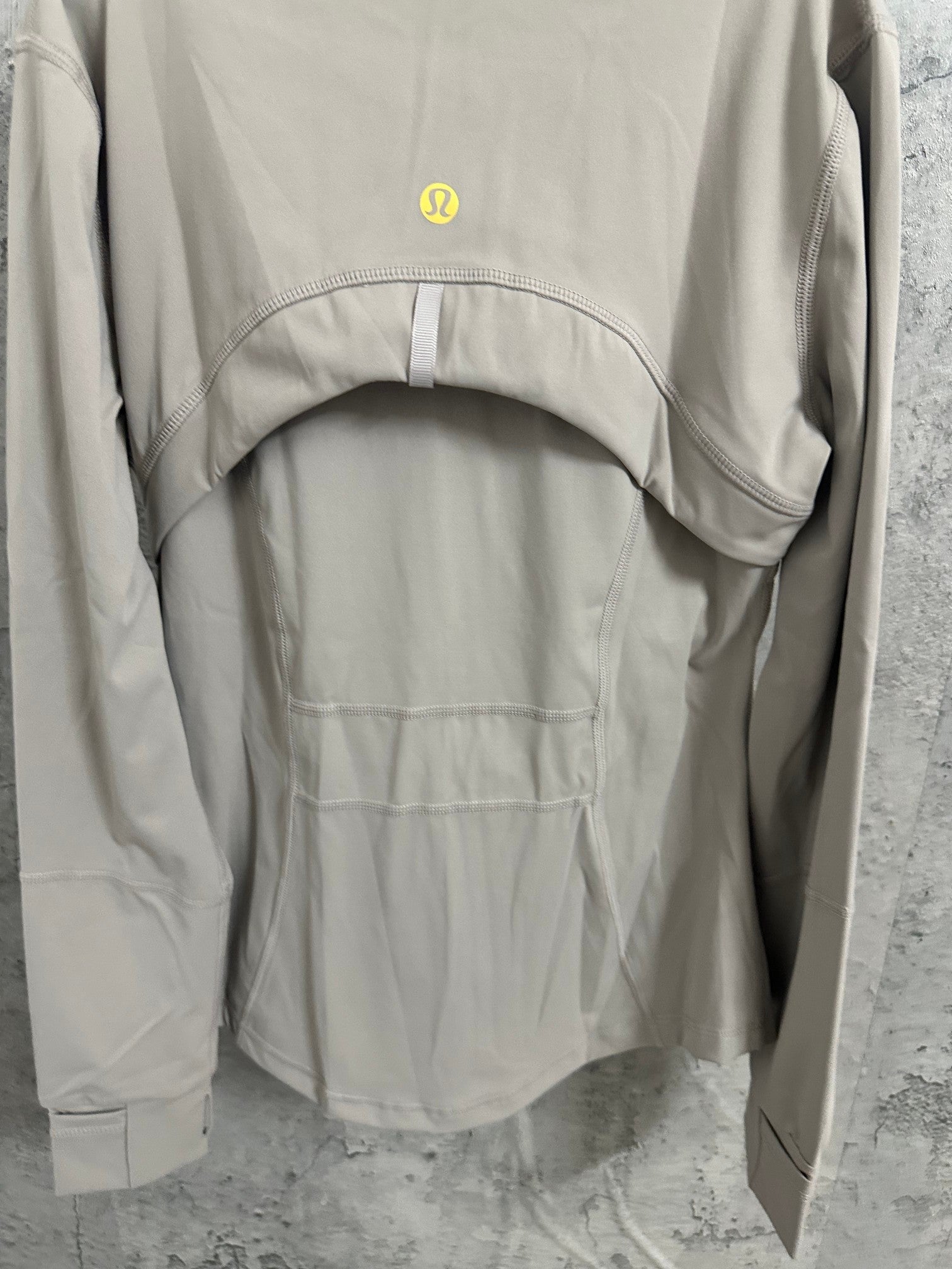Light beige jacket lower back view with panel lines and curved yoke seam