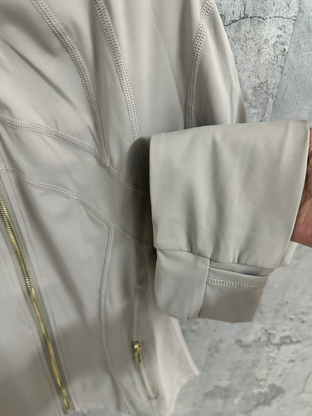 Light beige jacket sleeve cuff and hem detail with flap pocket