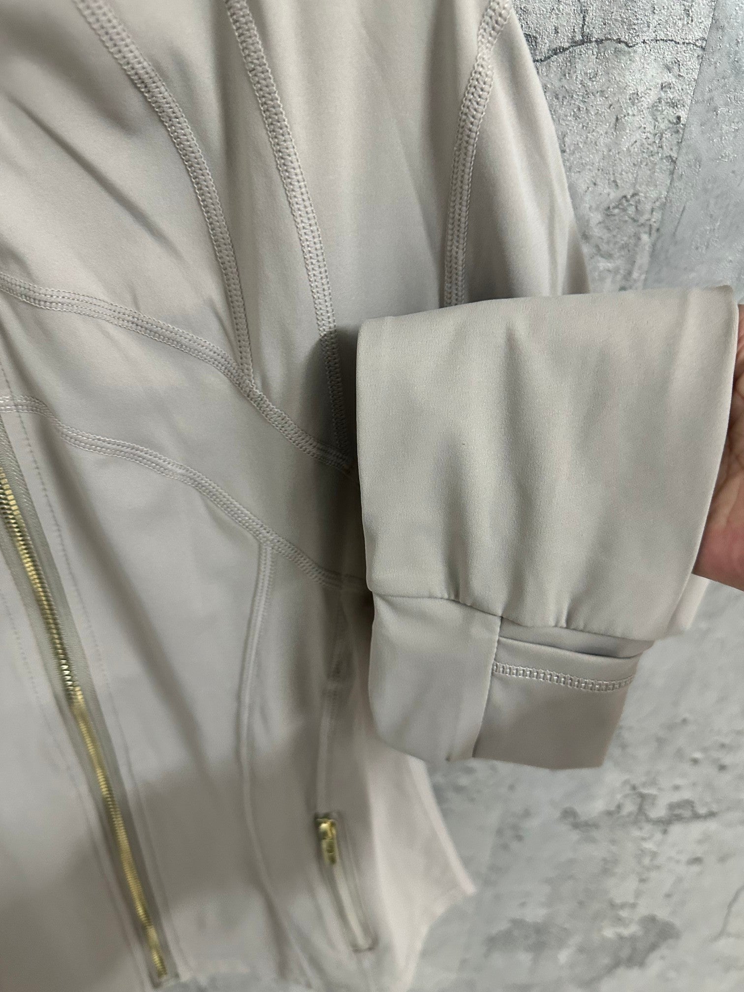 Light beige jacket sleeve cuff and hem detail with flap pocket