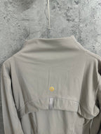 Light beige jacket back view with small yellow logo at upper back