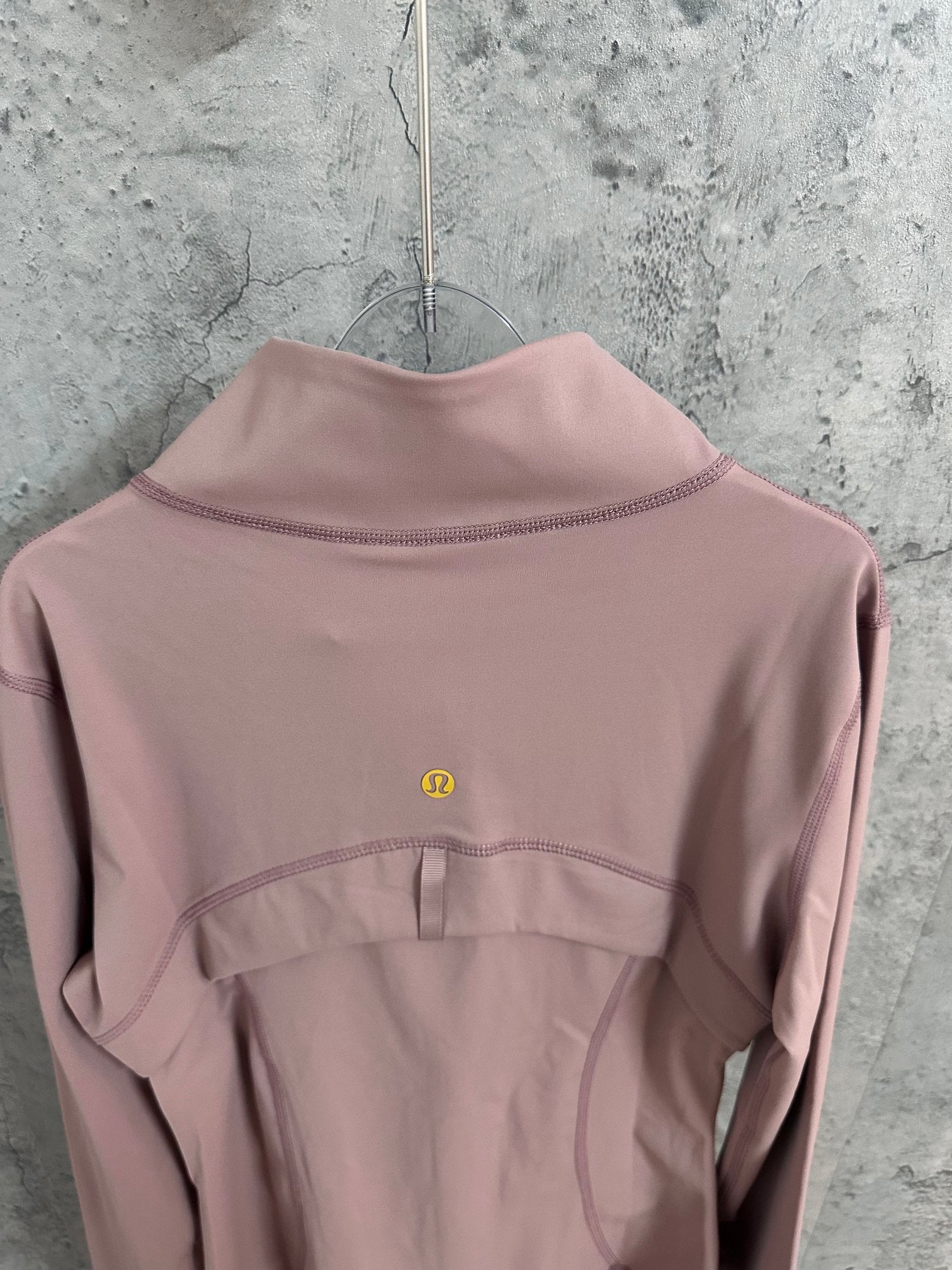 Dusty pink jacket back with small logo at upper back and stand collar