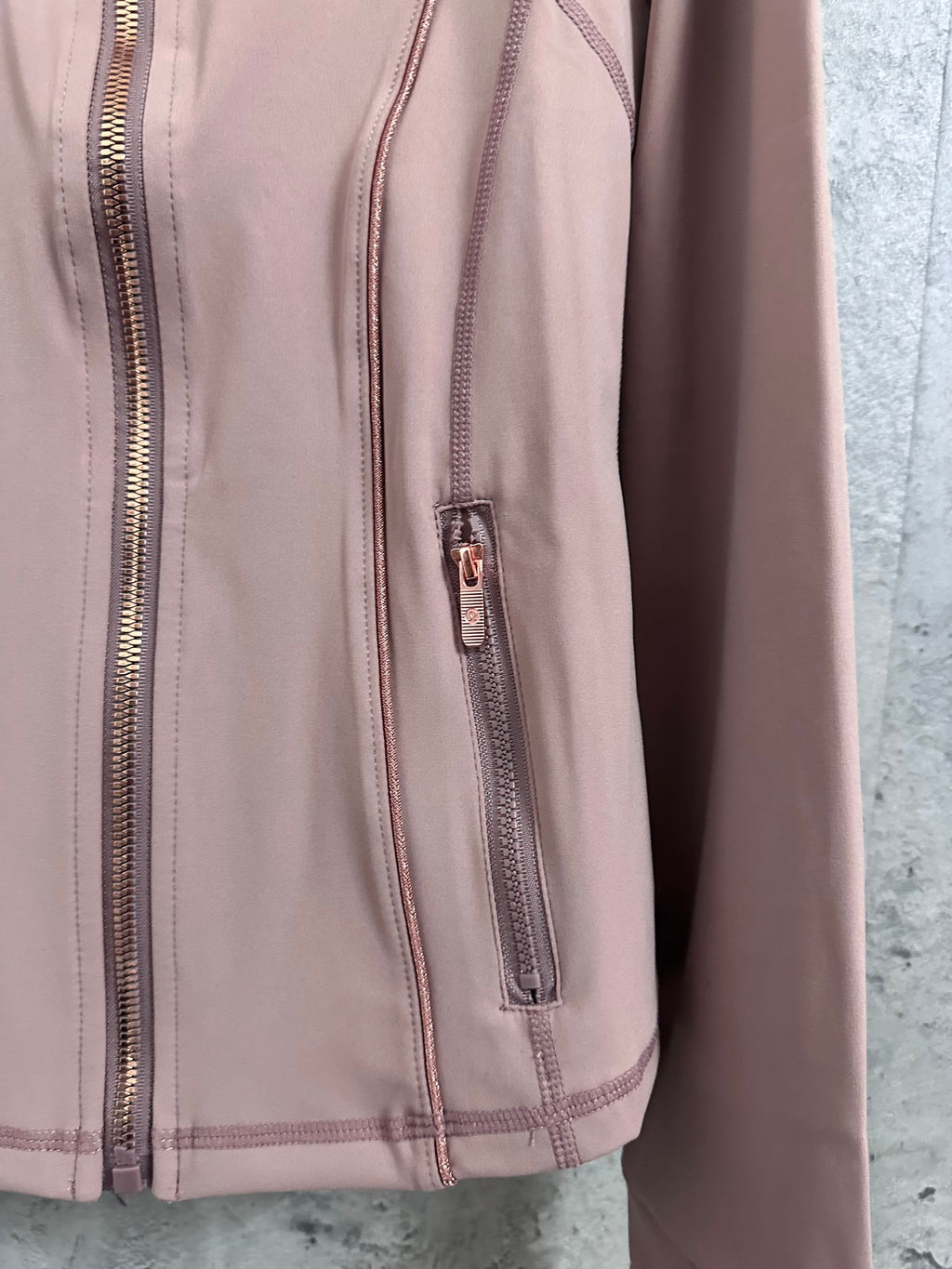 Dusty pink jacket side view with zipper pocket detail and contrast piping