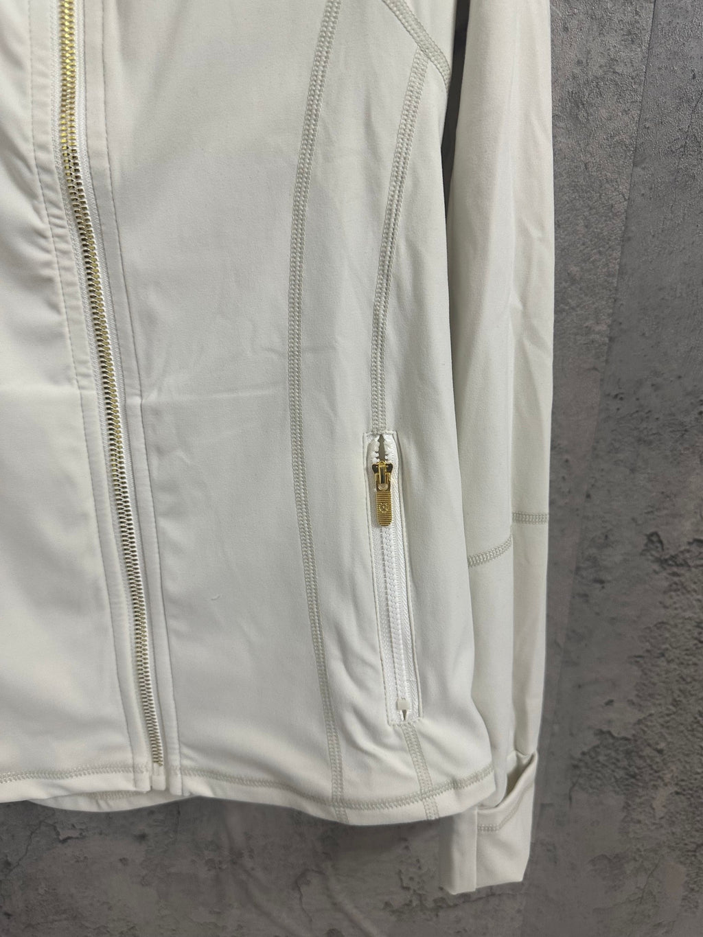 White zip-up jacket side view with gold-tone zipper pull and front trim