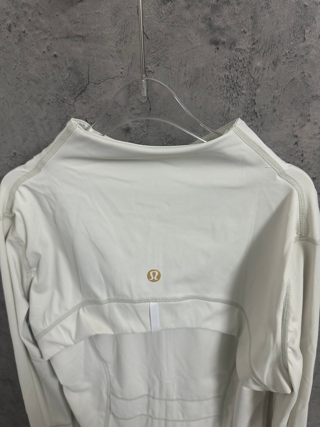 White zip-up jacket back view with small gold-tone logo and seam paneling