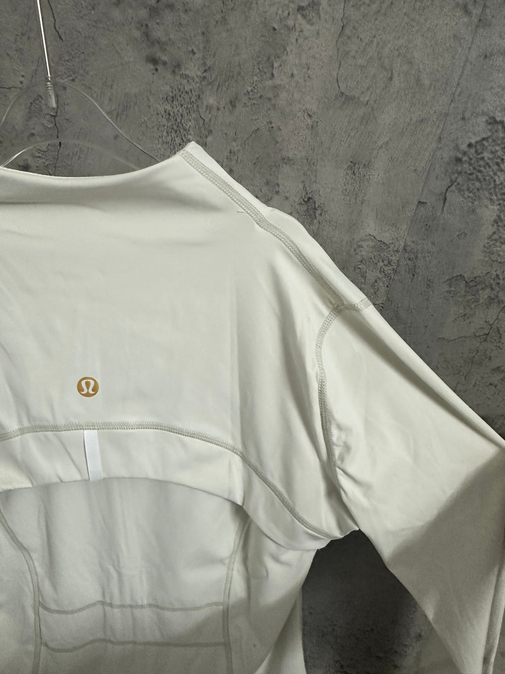 White zip-up jacket back view with small gold-tone logo on upper panel