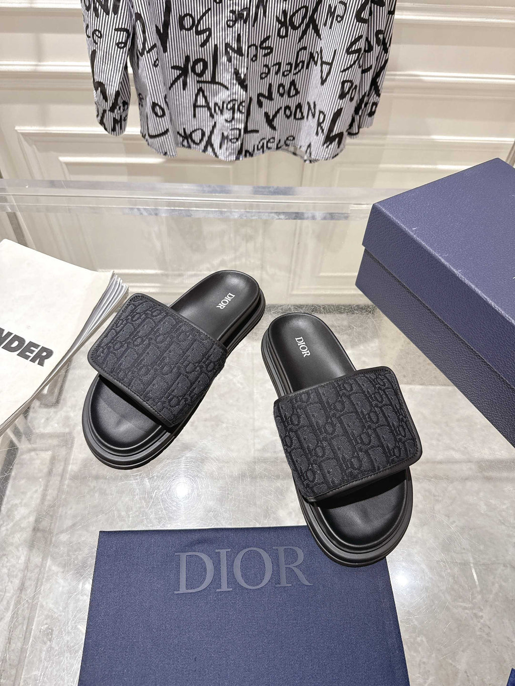 Black slide sandals with embossed monogram strap and stacked rubber sole