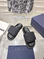Black slide sandals with embossed monogram strap and stacked rubber sole