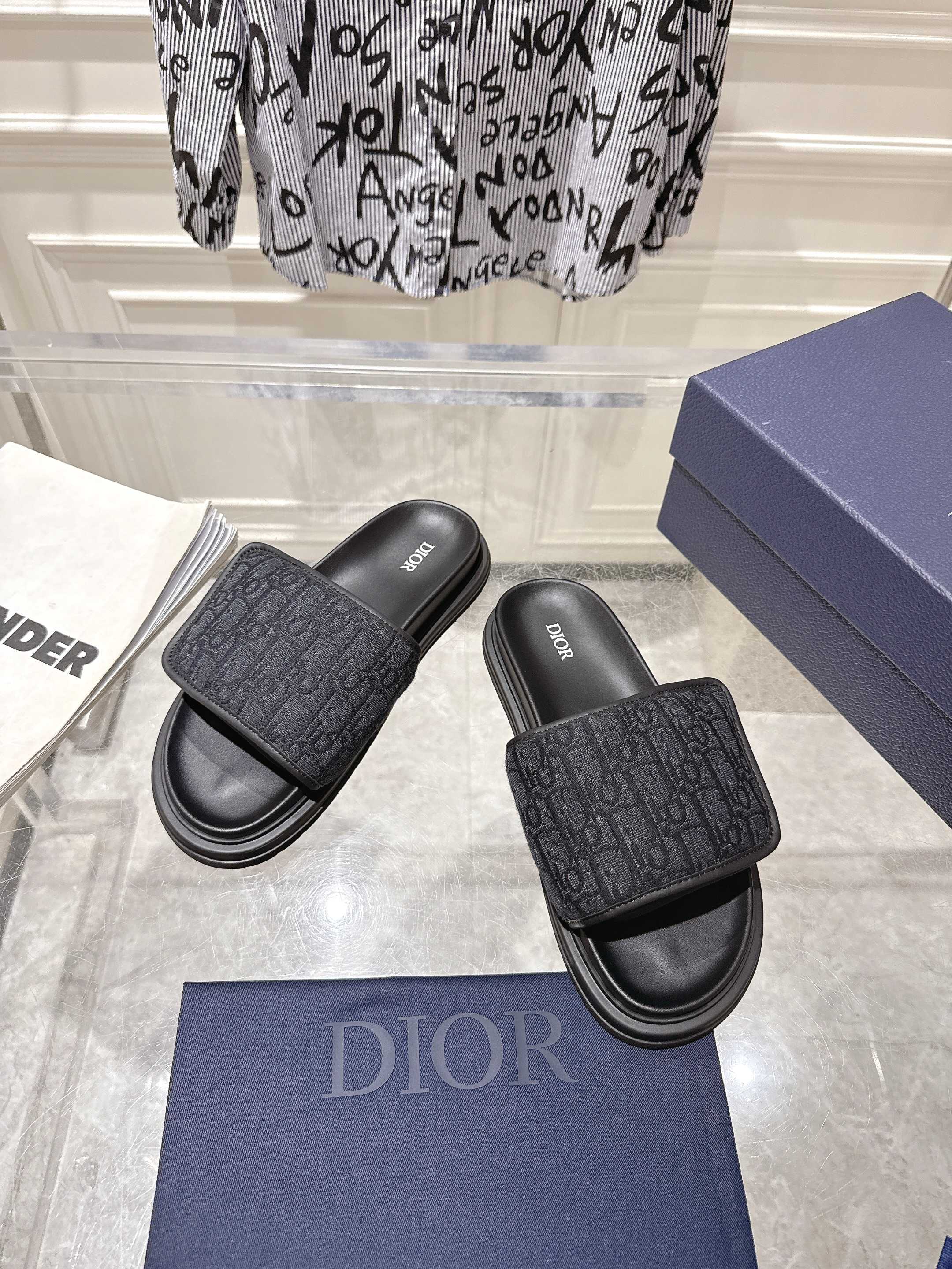 Black slide sandals with embossed monogram strap and stacked rubber sole