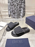 Pair of black Dior slide sandals with patterned front strap and thick sole