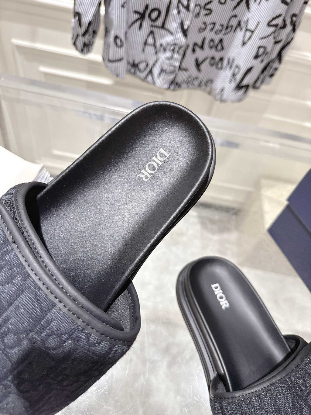 Black slide sandals close-up with embossed strap and “Dior” on footbed