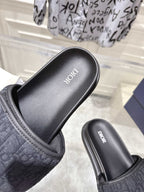Black slide sandals close-up with embossed strap and “Dior” on footbed