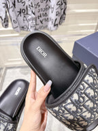 Dior slide sandal close-up; black cushioned footbed with Dior logo and patterned strap