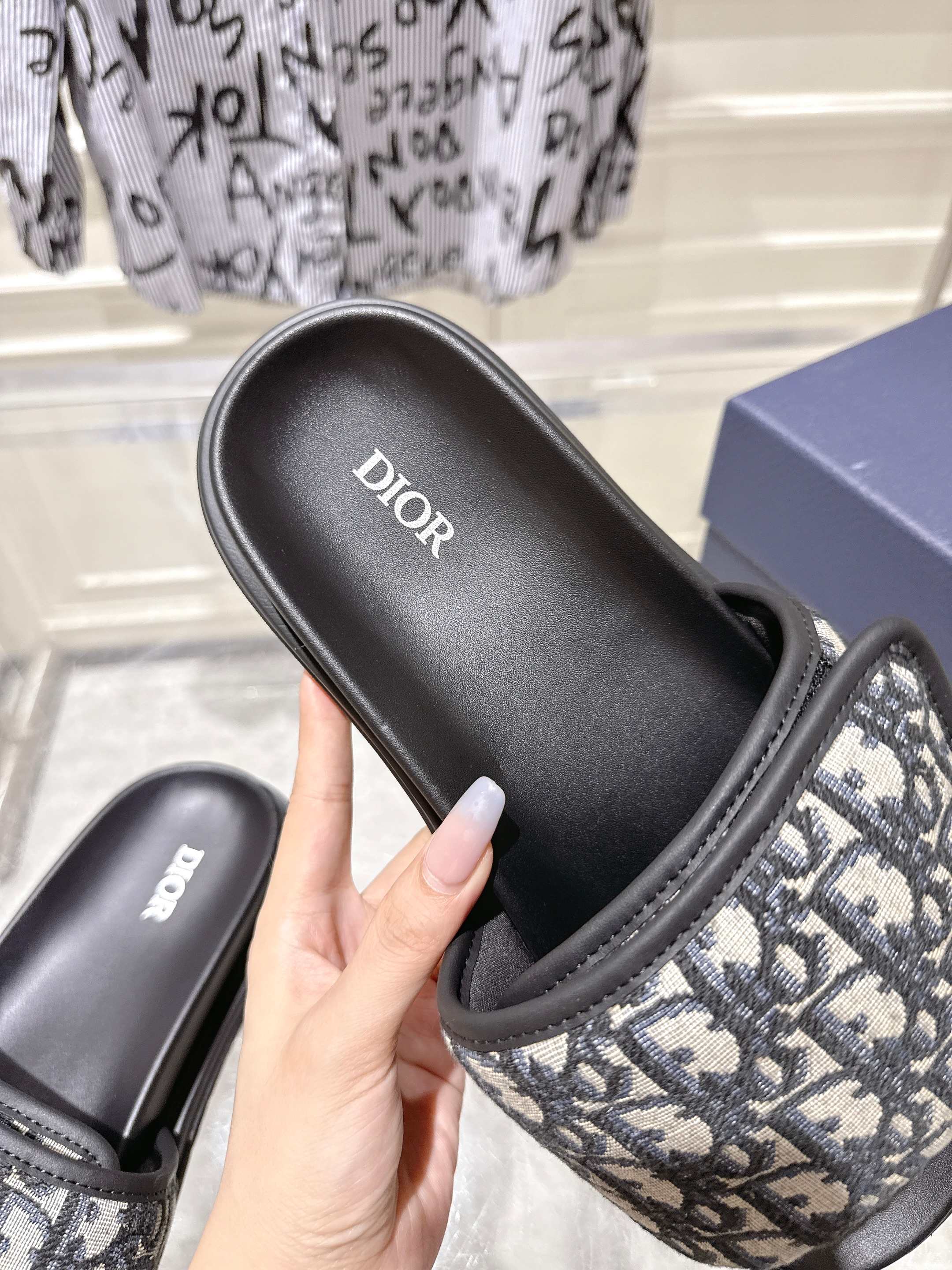 Dior slide sandal close-up; black cushioned footbed with Dior logo and patterned strap