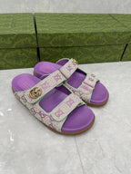 Gucci lilac slide sandals with GG monogram straps and gold buckle, rubber sole.
