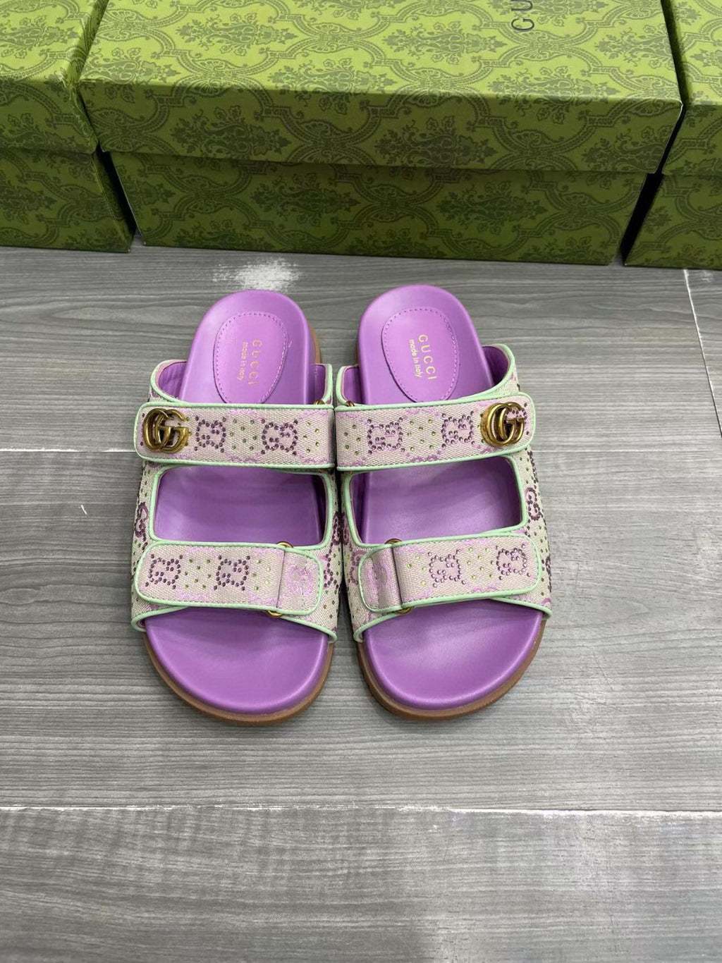 Gucci lilac slide sandals with two strap panels and gold-tone buckle hardware.