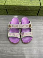 Gucci lilac slide sandals with two strap panels and gold-tone buckle hardware.