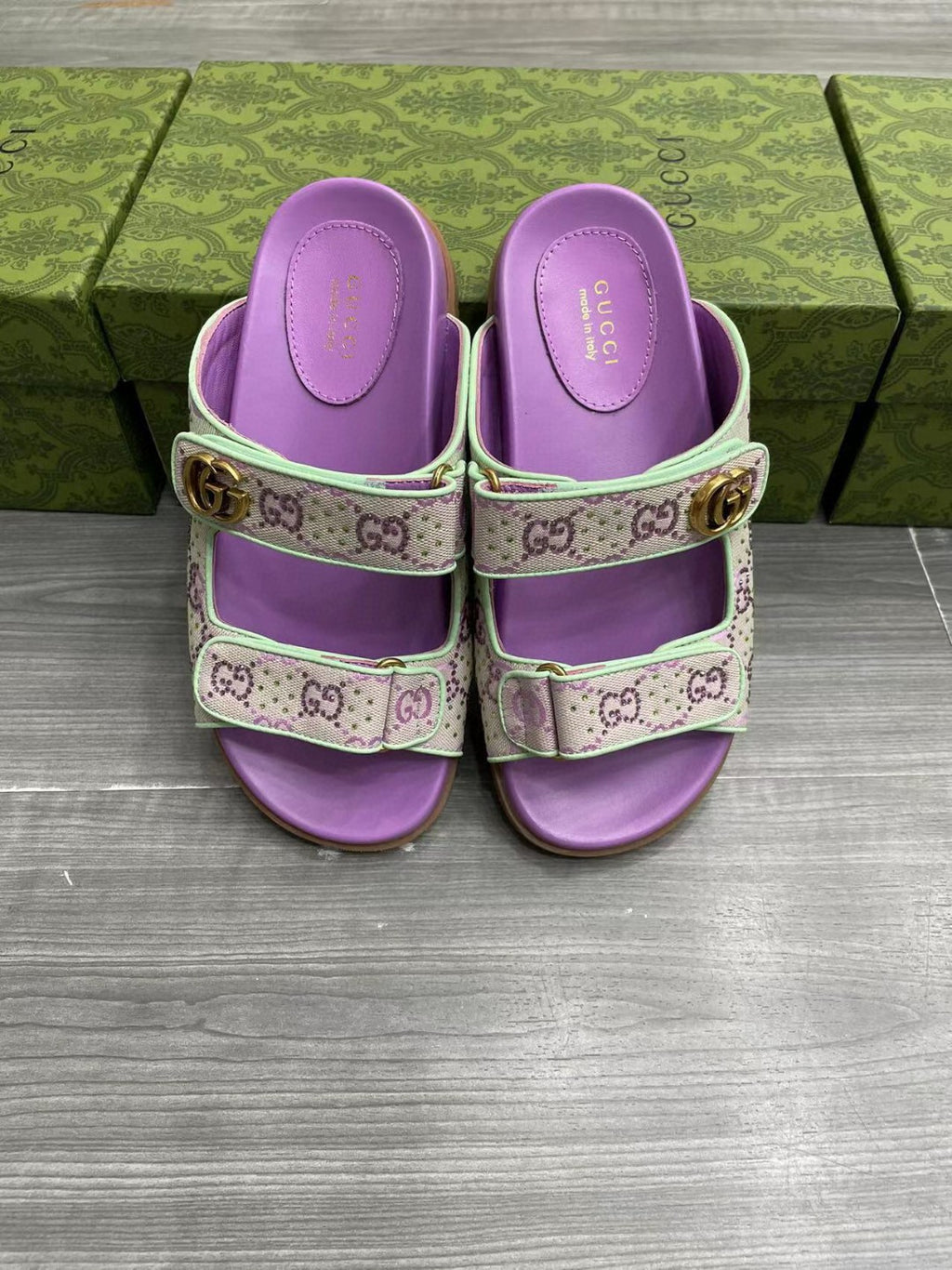 Gucci lilac slide sandals showing embossed footbed and gold-tone side buckle.