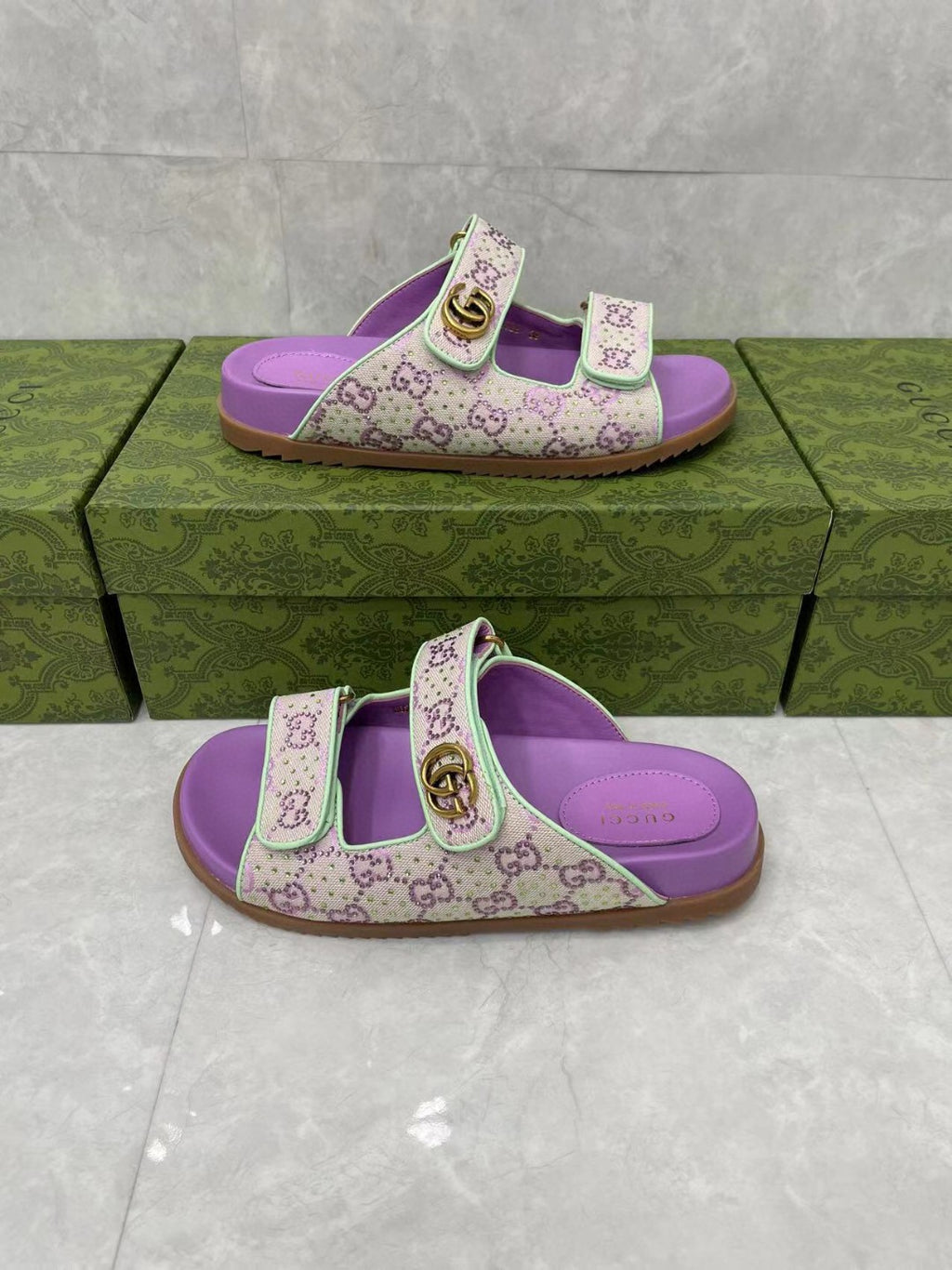 Gucci lilac slide sandals with open toe, patterned straps, and gold-tone buckle.