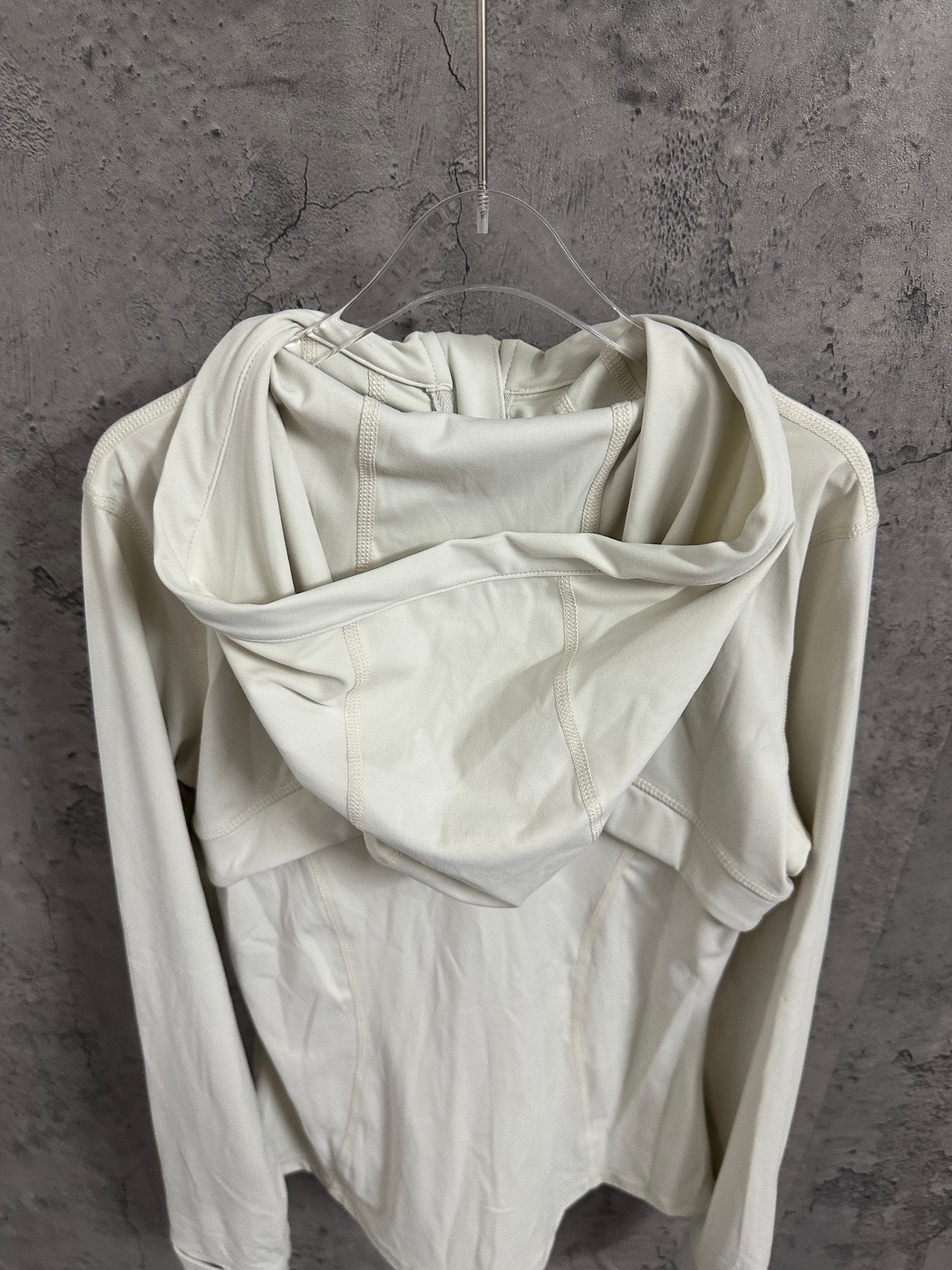 White hooded jacket back view with draped hood and relaxed shoulder fit.
