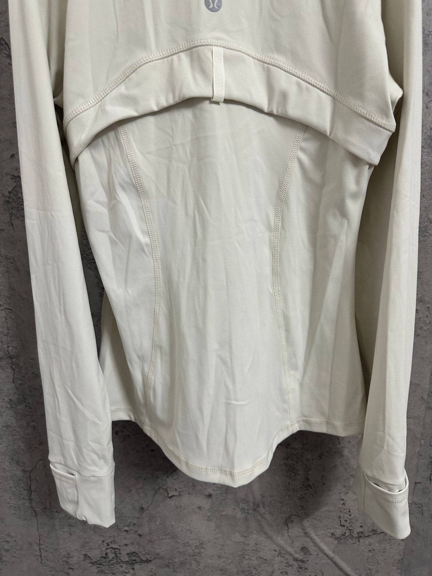 White hooded jacket back view with curved hem and hood yoke stitching detail.