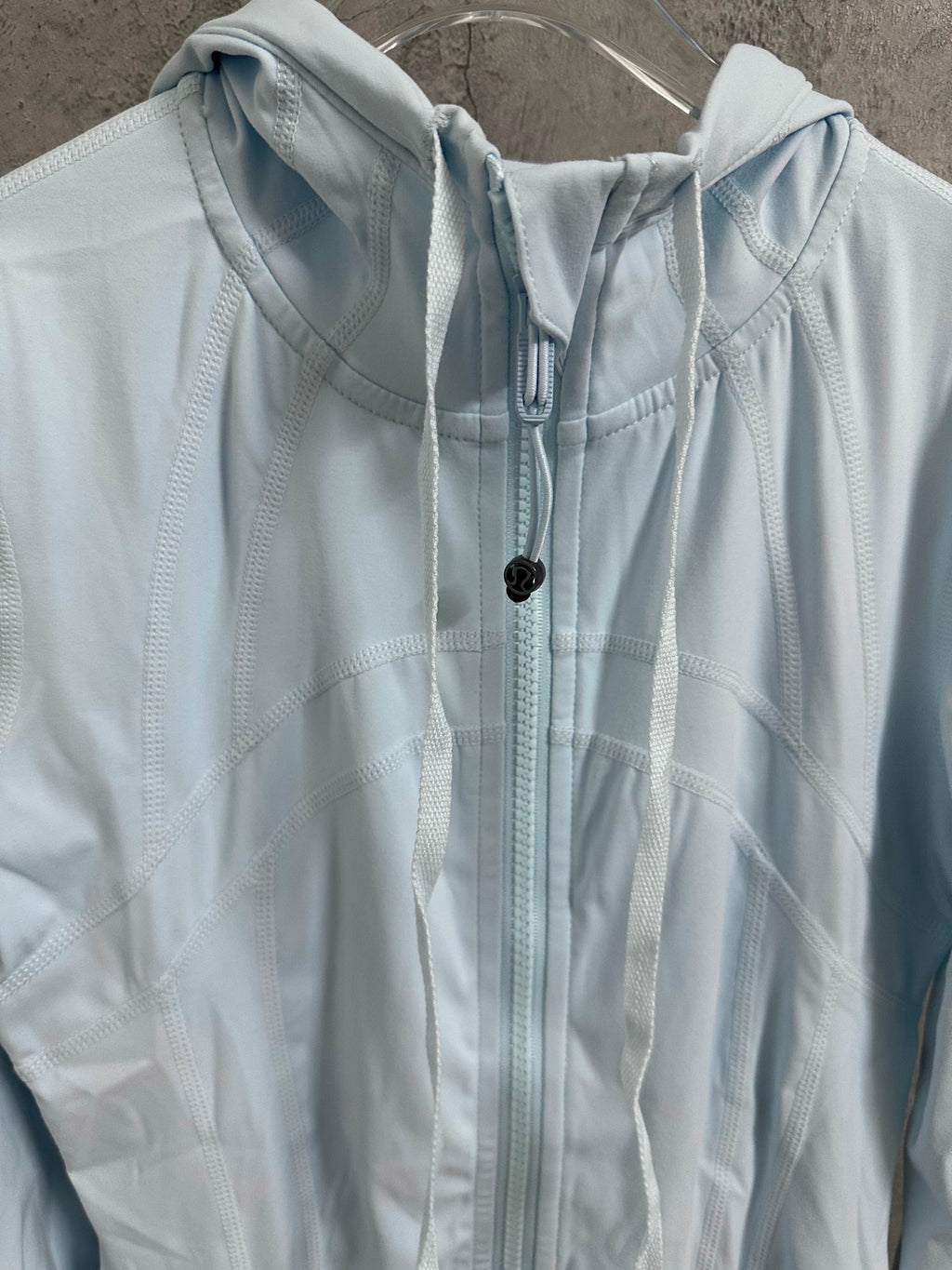 Light blue zip-up jacket close-up with hood and drawcord with dark toggle