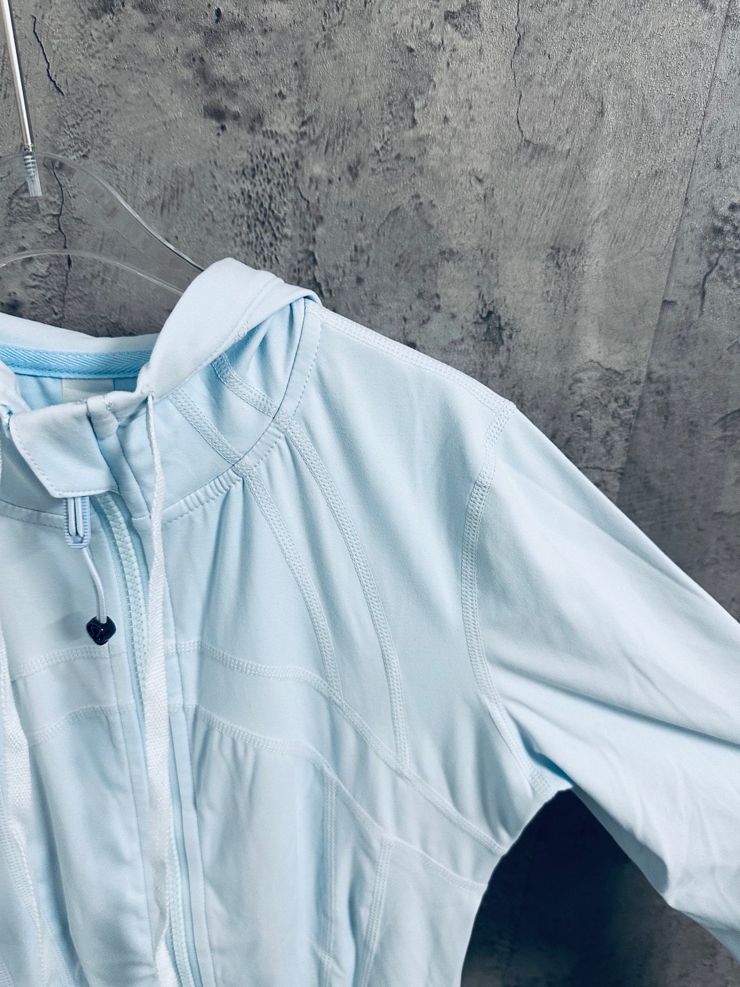 Light blue hooded zip jacket side view with front zipper and seams