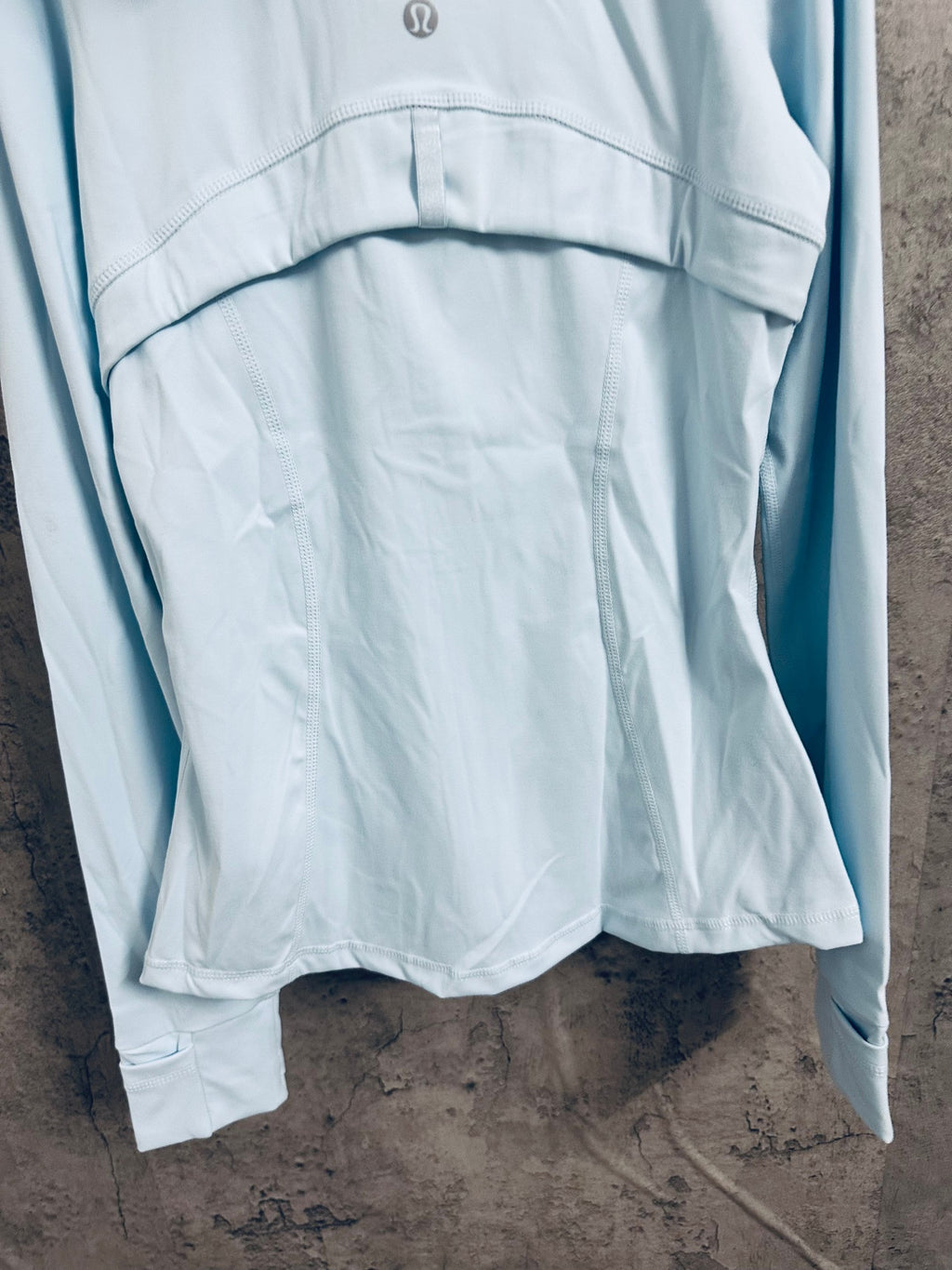 Light blue hooded zip jacket back hem with gathered fabric and curved seam