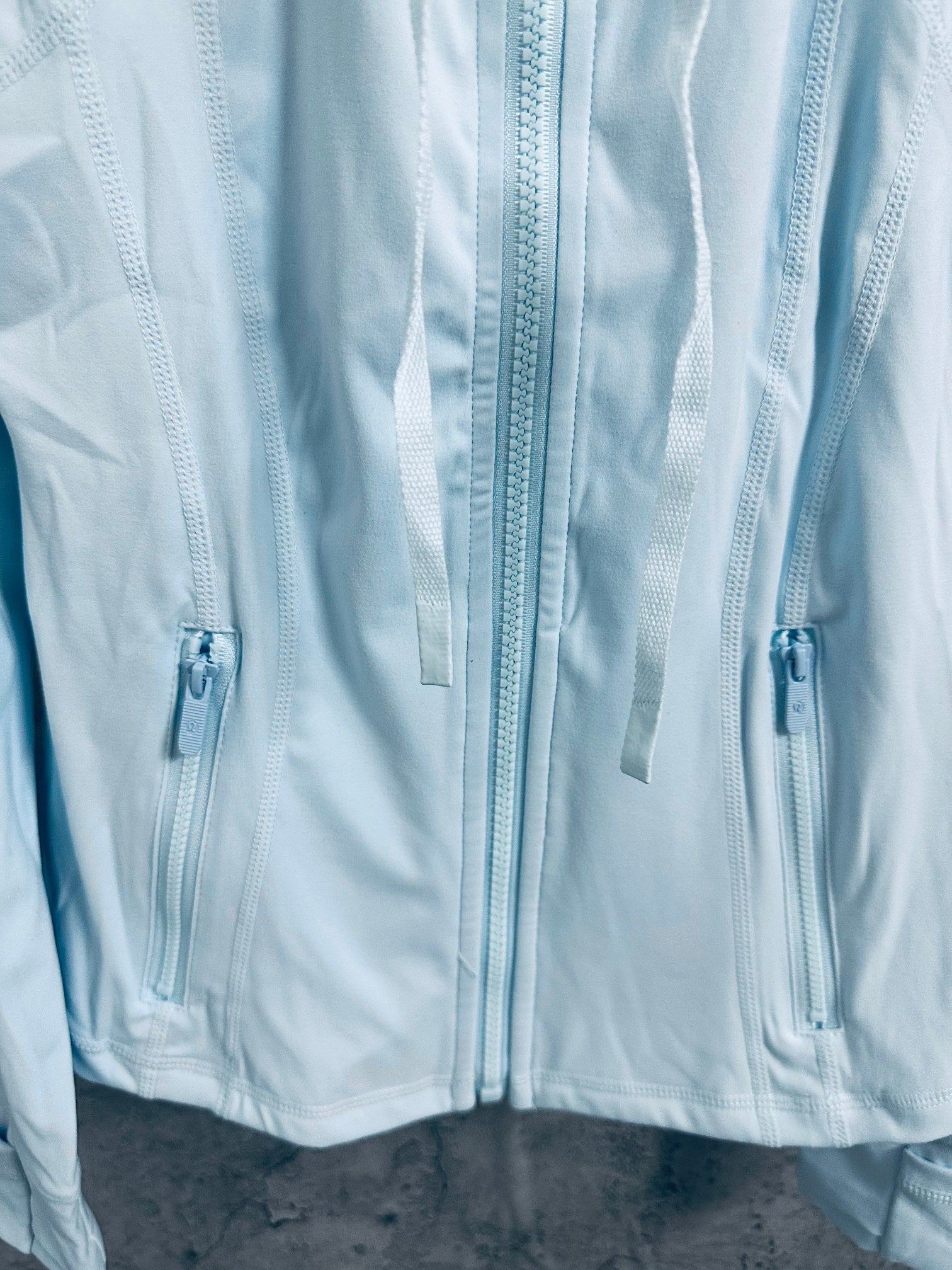 Light blue jacket front with triple zippers and metal pulls