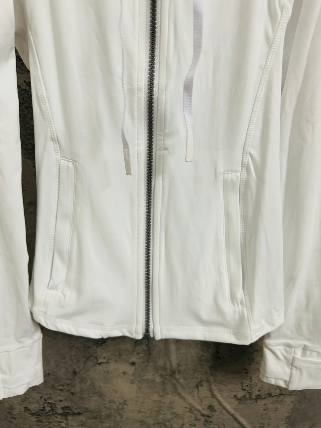 White jacket close-up of front zipper and side pockets with stitched seams