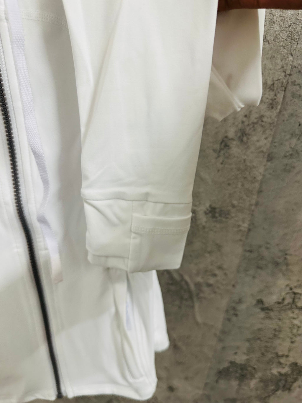 White jacket close-up of sleeve cuff and drawstring waist hem