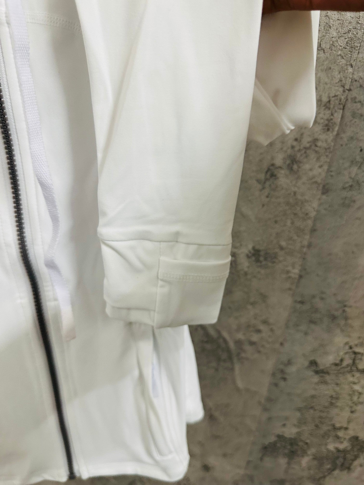 White jacket close-up of sleeve cuff and drawstring waist hem
