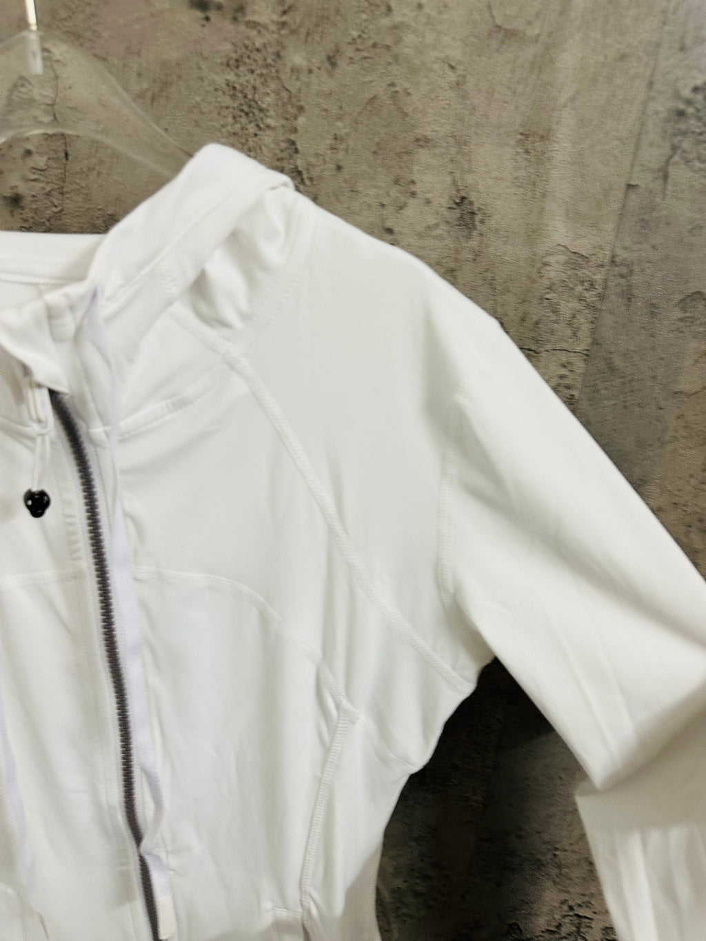 White jacket sleeve and shoulder close-up with zip front and hood edge