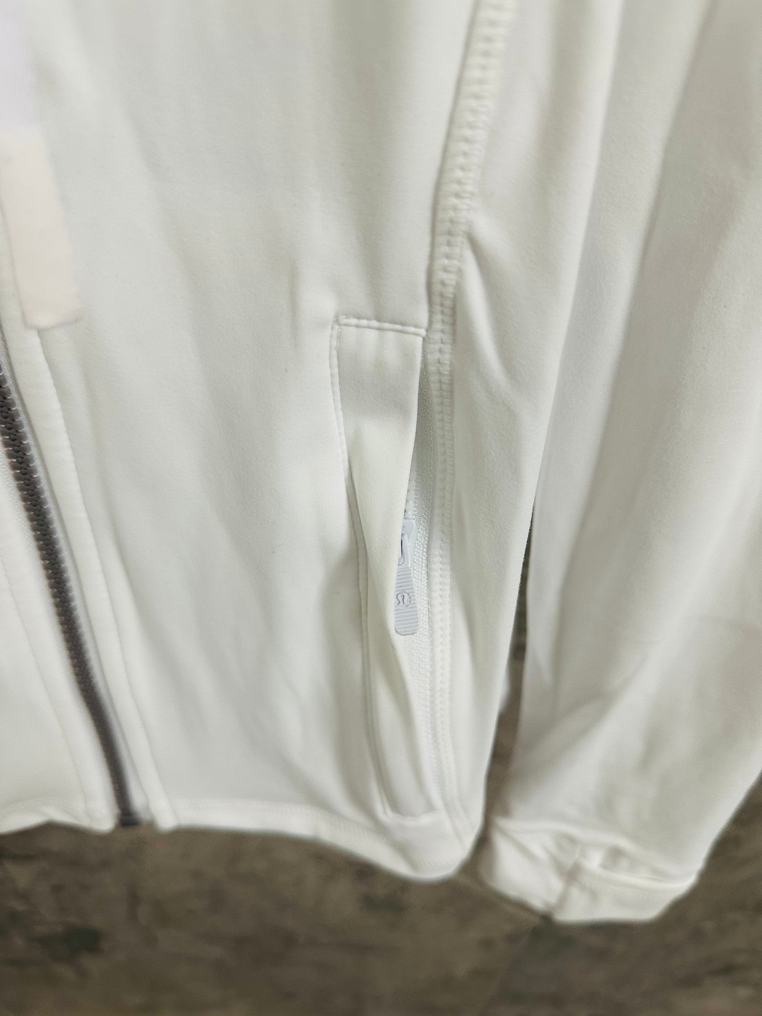 White jacket close-up of drawstring hem and pocket seam details