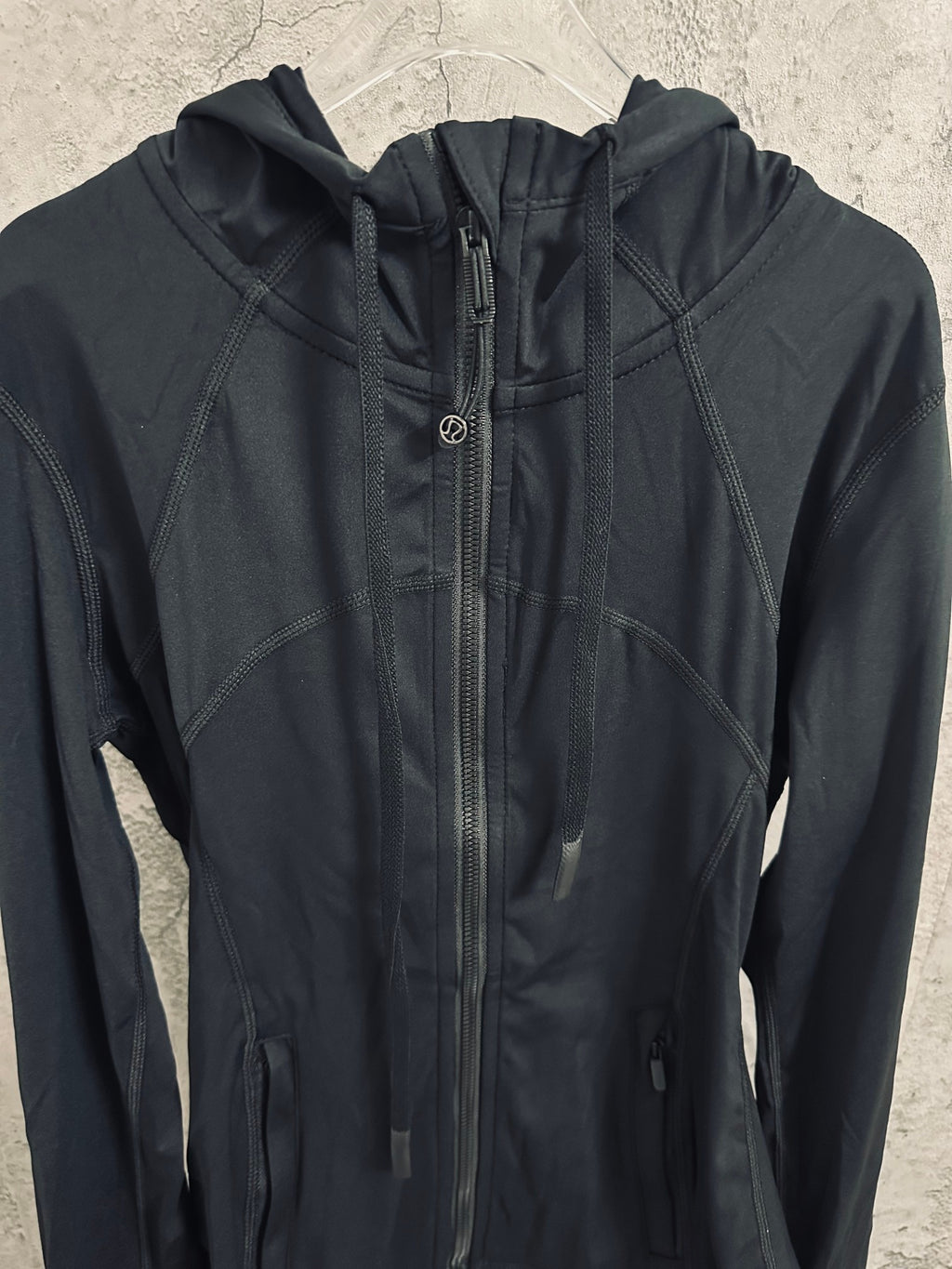 Dark hooded zip jacket with stand collar and zipper pull
