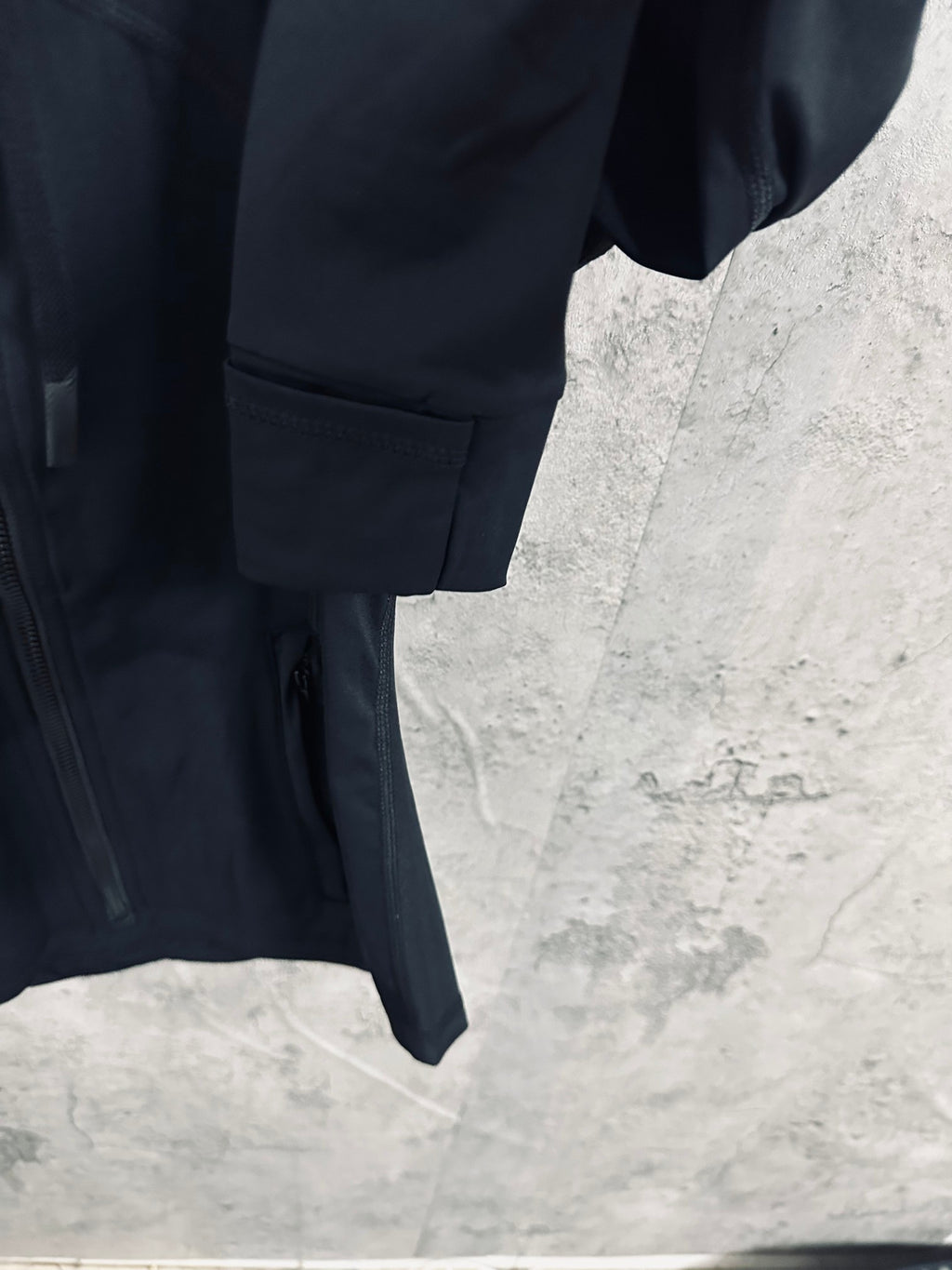 Dark jacket lower hem with pocket detail and rounded sleeve cuff