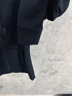 Dark jacket lower hem with pocket detail and rounded sleeve cuff