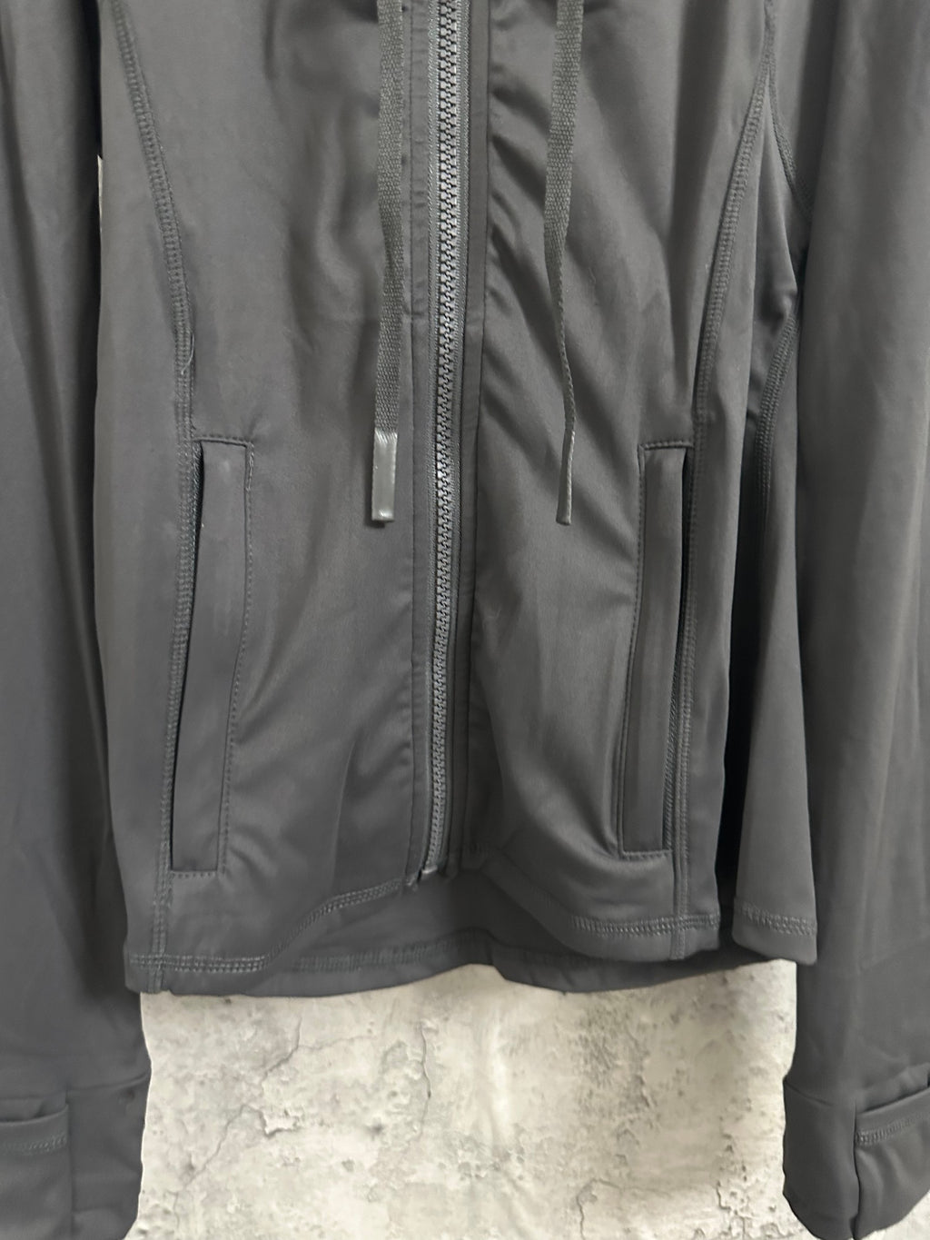 Dark zip jacket with front pockets and stitched panels near the zipper