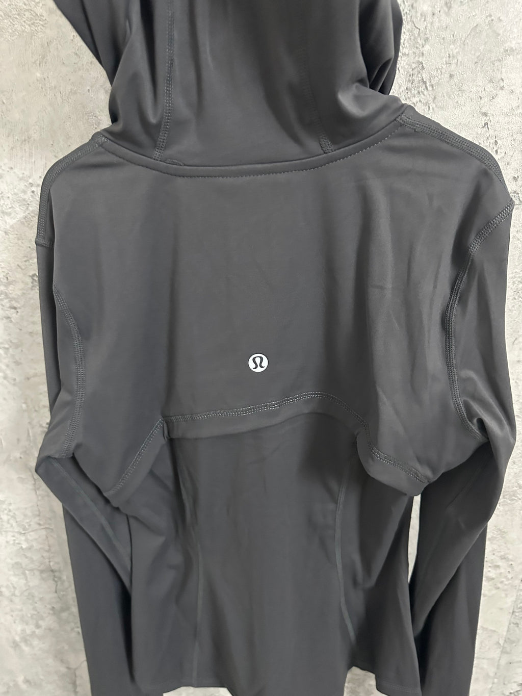 Dark hooded jacket back with small chest logo and curved yoke seam