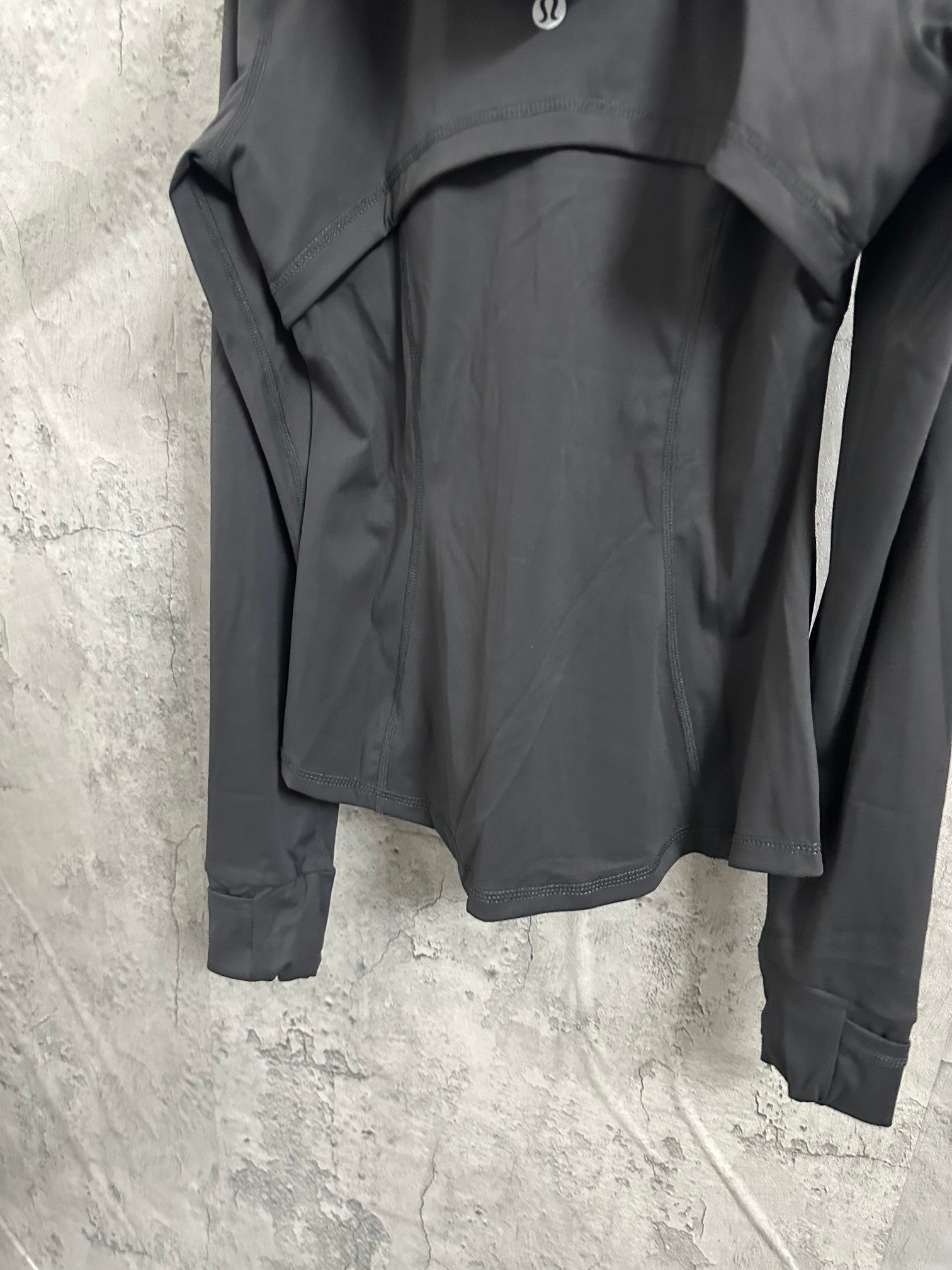 Dark hooded jacket back view with straight hem and side seams near cuffs