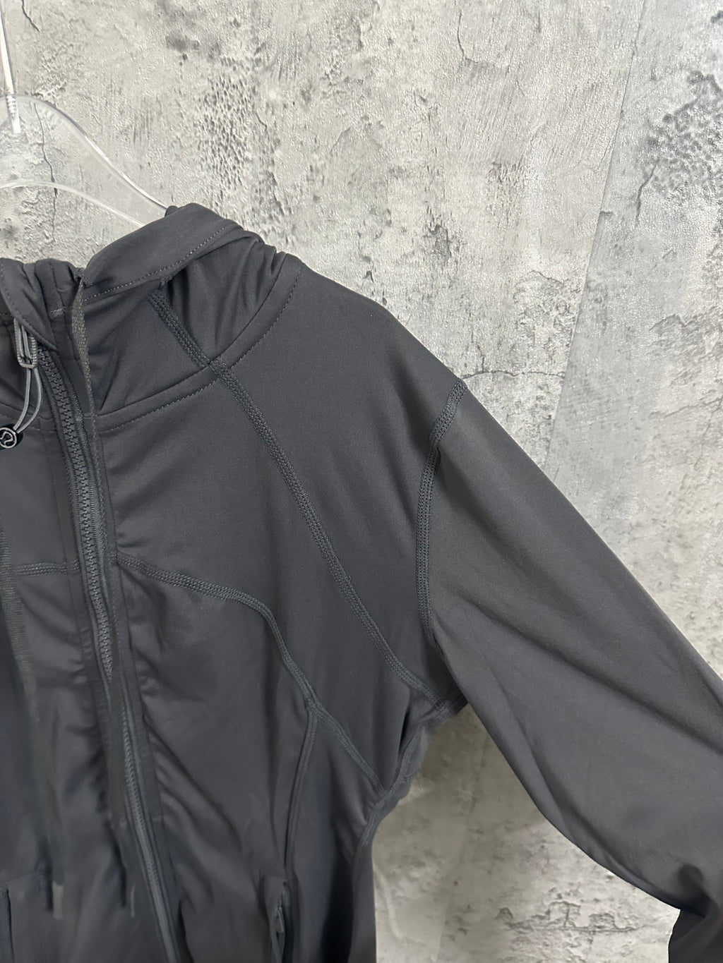 Dark hooded jacket sleeve and shoulder with curved stitched seam lines