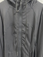 Dark hooded jacket detail with center zipper, drawstrings, and paneled stitching