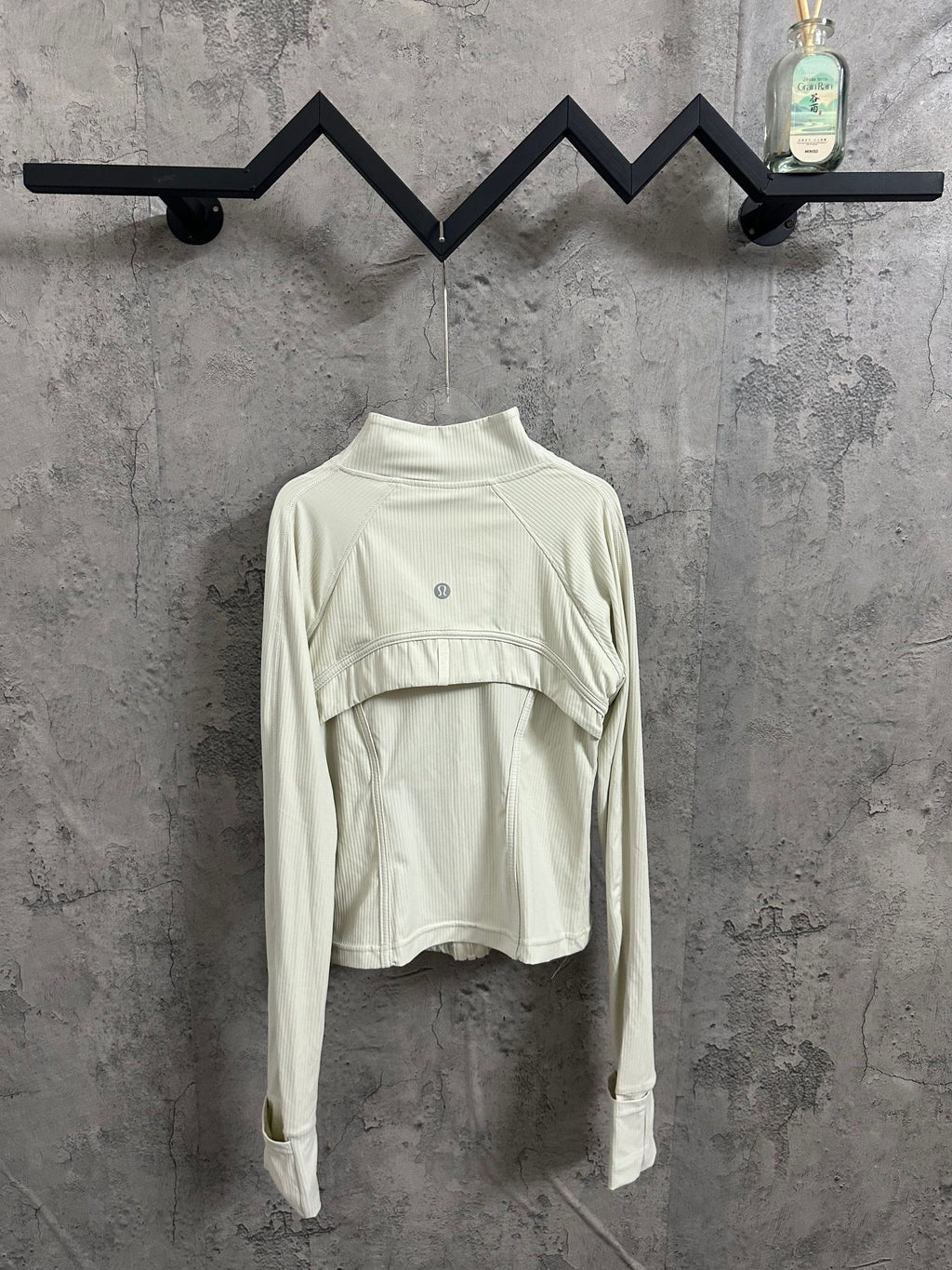 Light cream ribbed high-neck jacket with curved yoke seam and small circular chest logo