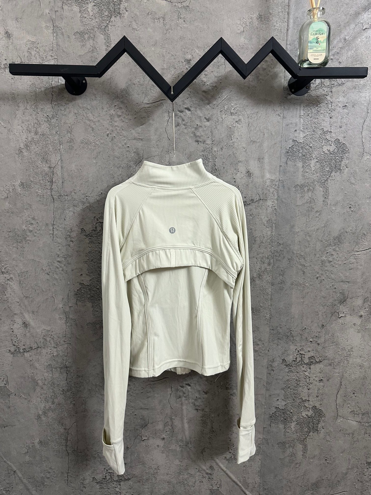 Light cream ribbed high-neck jacket with curved yoke seam and small circular chest logo