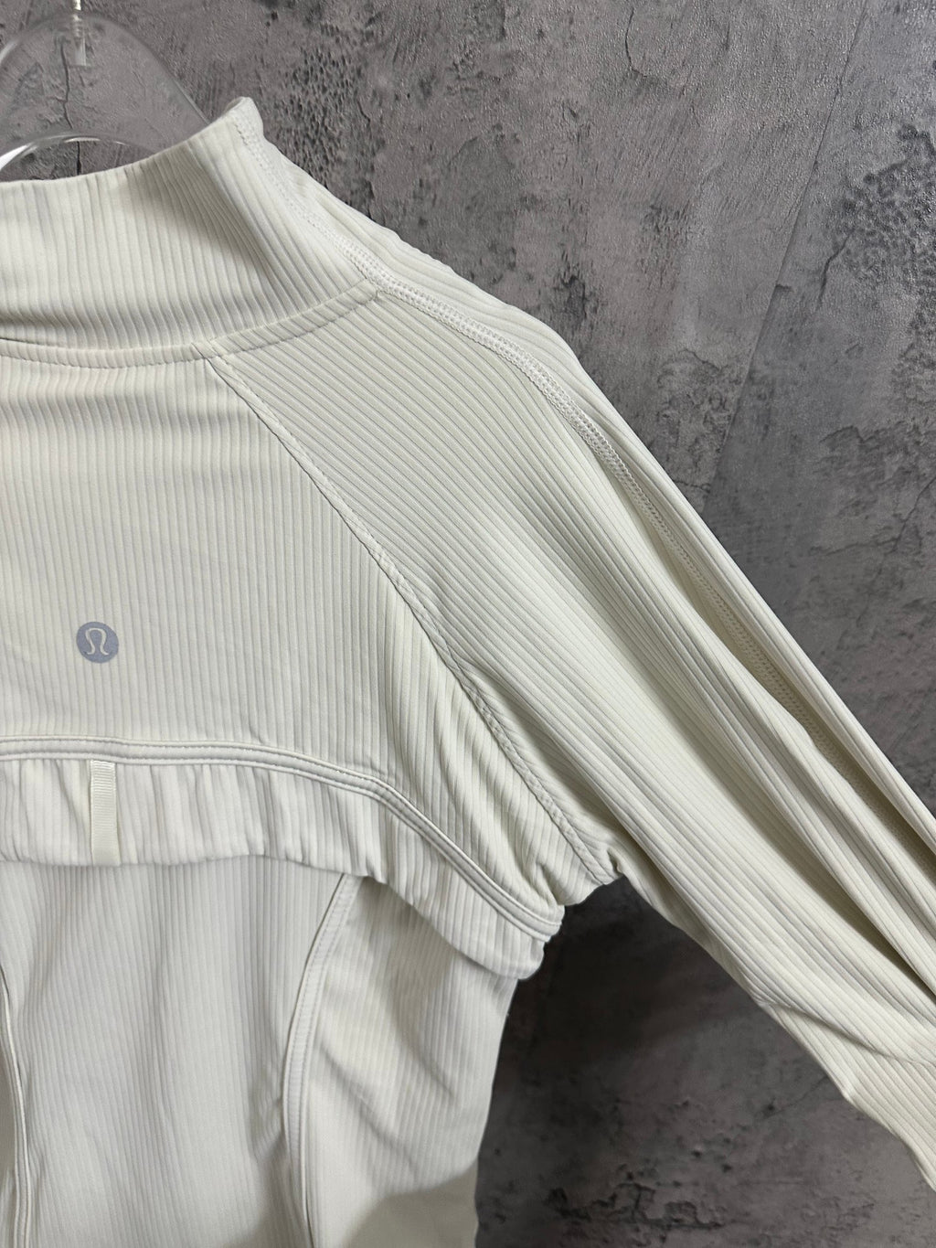 Light cream ribbed jacket with high neck and side seam detail near sleeve hem