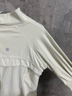 Light cream ribbed jacket with high neck and side seam detail near sleeve hem