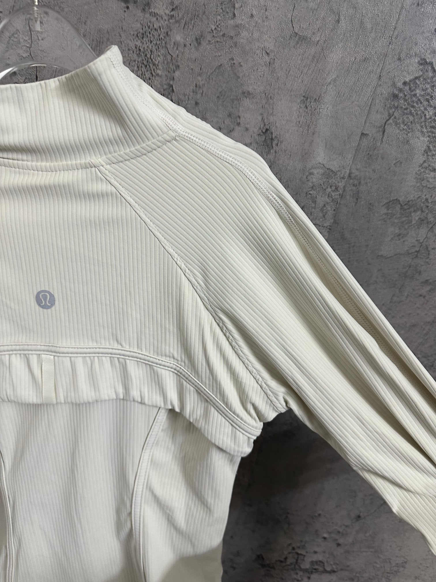 Light cream ribbed jacket with high neck and side seam detail near sleeve hem
